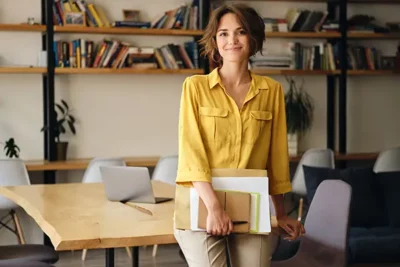 Femme souriante avec une chemise jaune assise sur le bord d'une table